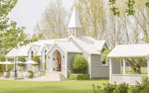 White chapel with steeple on manicured lawn with mature trees