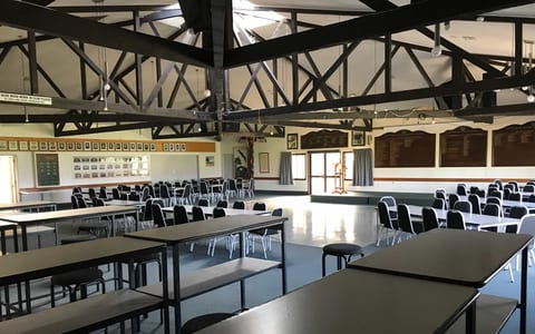 Large club hall with exposed dark timber roof trusses, tables, and club memorabilia on walls