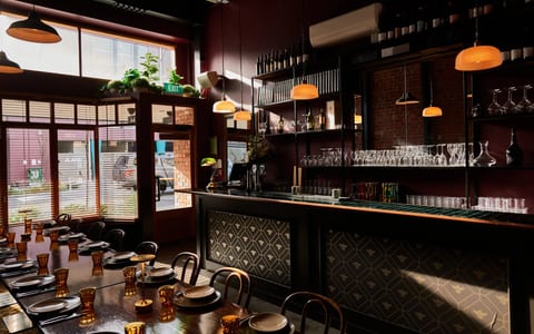 Deep red-walled dining room with patterned tile bar front, amber pendant lights and long table setting