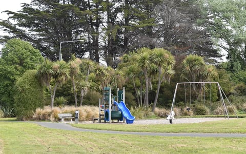 Park playground with slide, swings and trees