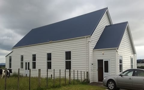 White weatherboard hall with blue iron roof, set in rural paddock
