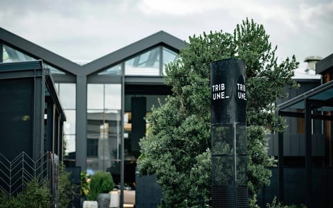 Dark-clad venue exterior with peaked gable glazing and branding signpost