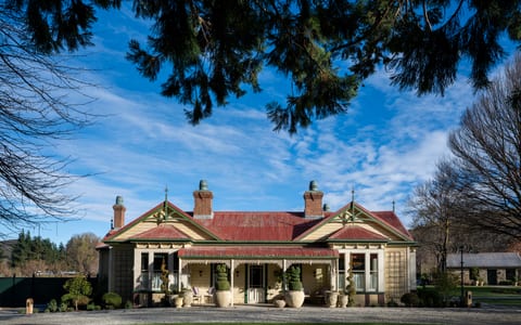 Victorian homestead building at Ayrburn with ornate verandah, topiary urns, and open lawn in foreground