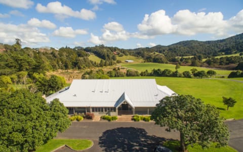 Aerial view of a large white-roofed event centre building set in rural farmland