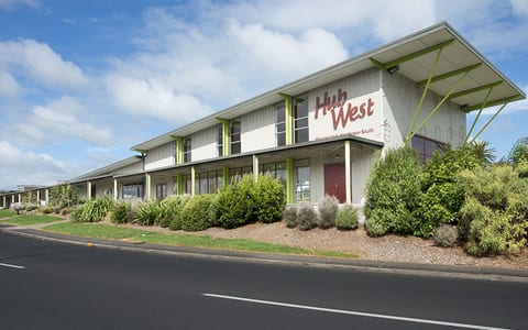 Two-storey community centre building with Hub West signage, green accents and landscaped frontage