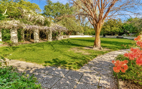 Formal garden with stone pergola, lawn, and flowering plants