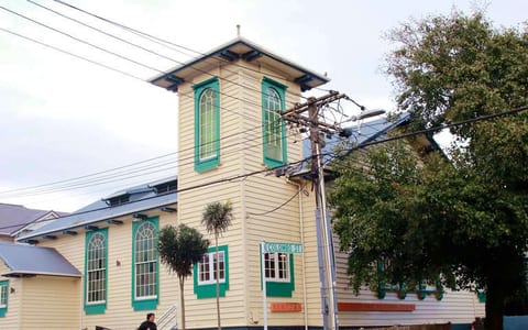 Two-storey timber church building painted cream and teal with corner tower
