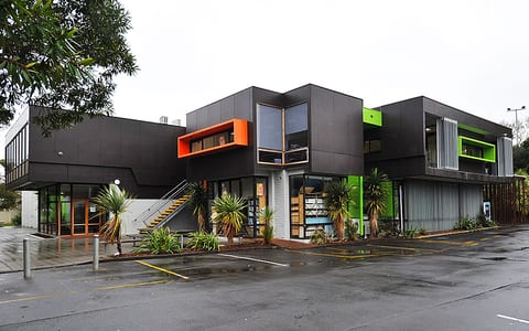 Contemporary dark-cladded two-storey building with bold orange and green accents