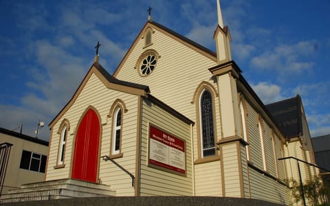 Timber-clad church exterior with steeple, arched windows and red door