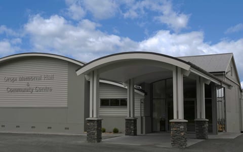 Contemporary curved-roof community hall with stone-clad entrance columns and signage