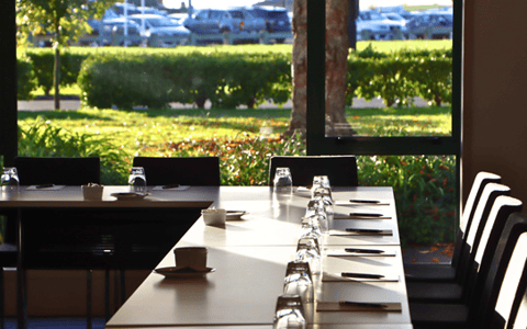 Conference room with boardroom table set for a meeting, garden views through windows