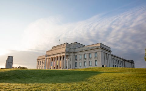 Classical stone museum building on open grass field