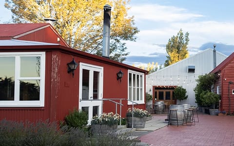 Red painted timber buildings with a courtyard, barrel planters, and autumn trees