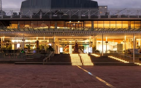 Large civic building exterior at dusk with illuminated entrance and plaza