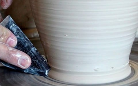 Hands shaping clay on a pottery wheel