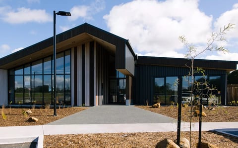 Single-storey dark-clad building with large glazed entry and timber accents
