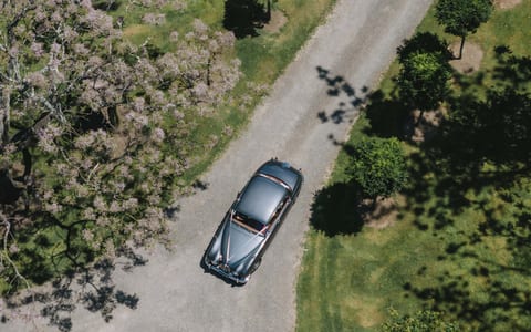 Aerial view of classic car on gravel drive through venue grounds