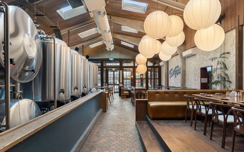 Brewery interior with stainless fermentation tanks, timber ceiling and pendant lights