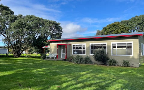 Small rural hall with green cladding, red roof trim, and lawn surrounds