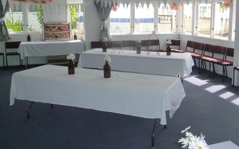 Hall room set up for a function with trestle tables, white cloths, bunting and decorations