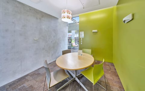 Small meeting room with round table, lime-green accent wall and pendant light