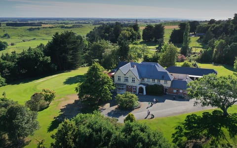 Aerial view of golf clubhouse and grounds amid trees and fairways
