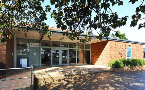 Single-storey brick and glass community building with paved forecourt