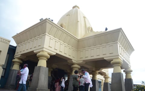 Ornate building entrance with columns and a dome structure, people gathered at the door