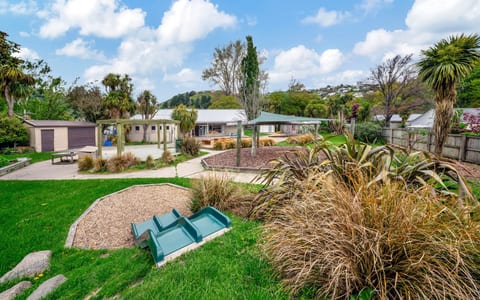 Outdoor grounds with garden beds, trees and small playground equipment