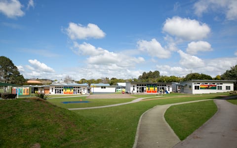 School buildings and playground on open lawn under blue sky