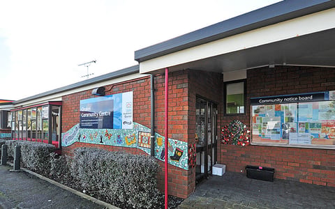 Single-storey brick community centre entrance with mosaic artwork and notice board