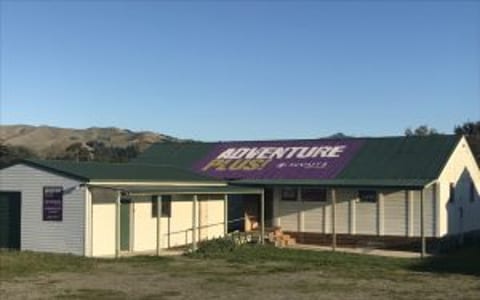 Small single-storey hall with painted Adventure Plus signage on roof