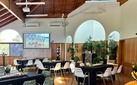 Hall with timber vaulted ceiling, arched windows, tables set with black cloths