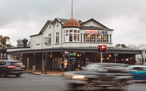 Historic two-storey white timber building on a street corner with copper dome detail