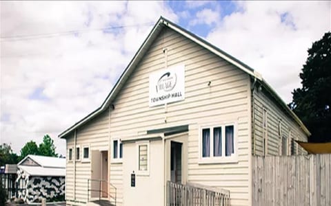 Cream weatherboard township hall with gabled roof and a Village Township Hall sign