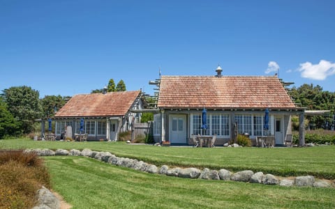 Low timber and stone villa buildings with cedar shingle roof on green lawn