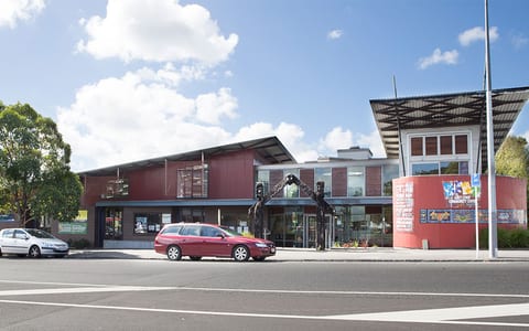 Contemporary community centre building with red cladding and street sculpture