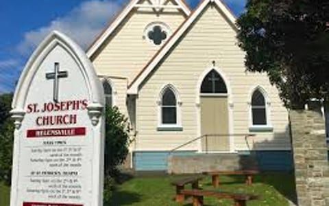 Small white wooden church with Gothic windows and sign