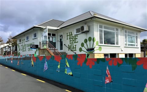 Single-storey white weatherboard community centre with colourful mural on boundary wall
