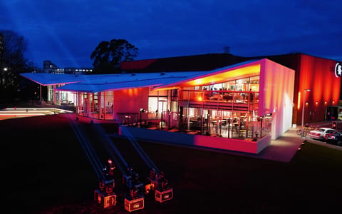 Contemporary building with red and orange cladding lit up at night