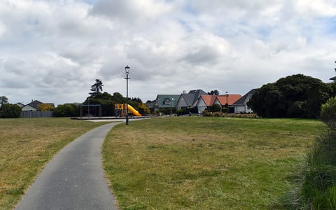 Open park with path, playground equipment and surrounding houses