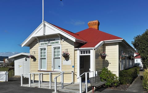 Clevedon District Centre small heritage building with red roof and NZ flag