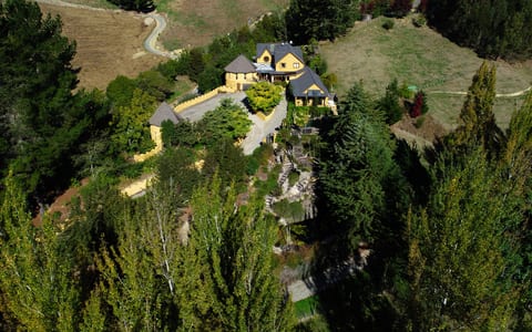 Aerial view of yellow stone castle-style building set into wooded hillside
