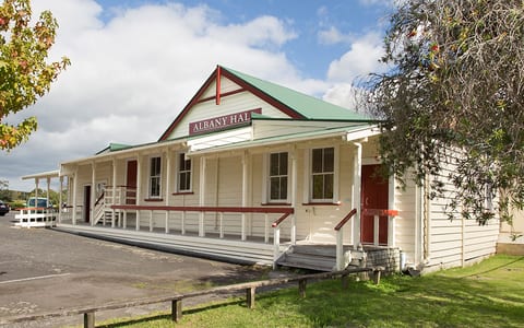 Heritage weatherboard hall with verandah, green roof, and red trim
