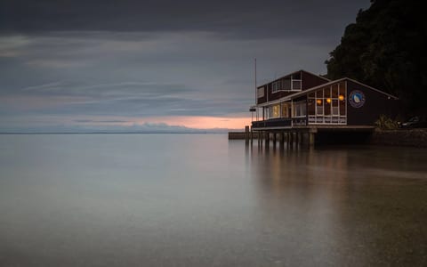 Timber clubhouse building on piles over water at dusk