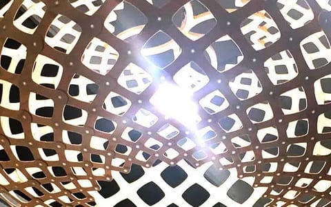 Close-up of a round woven pendant light fitting against a white ceiling