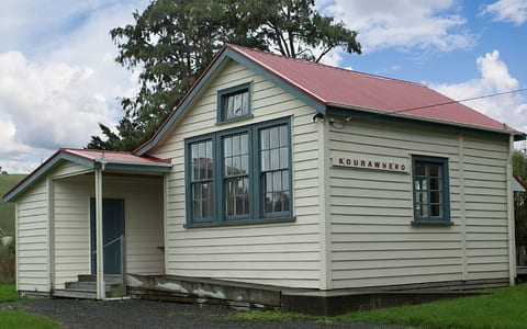 Small weatherboard hall with red roof and covered entry porch