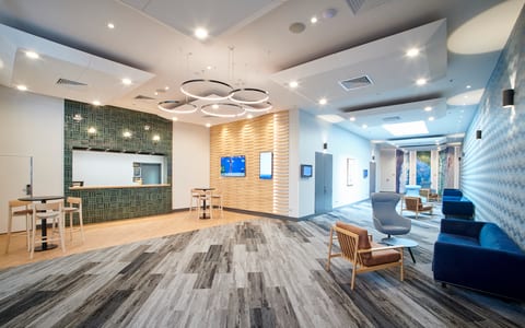 Contemporary hotel lobby with circular pendant lighting, tiled feature wall, striped carpet, and lounge seating