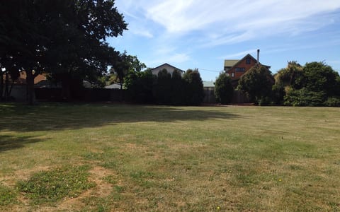 Open lawn area with trees at boundary and residential buildings beyond
