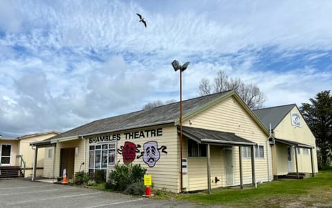 Yellow weatherboard Shambles Theatre building with painted masks on facade